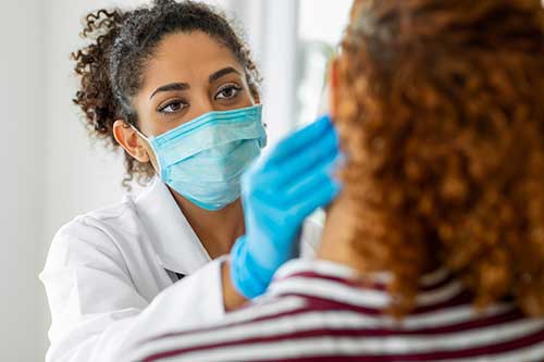 female dentist looks at patient's lip who is suffering from cold sores